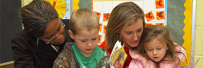 students reading a book to children