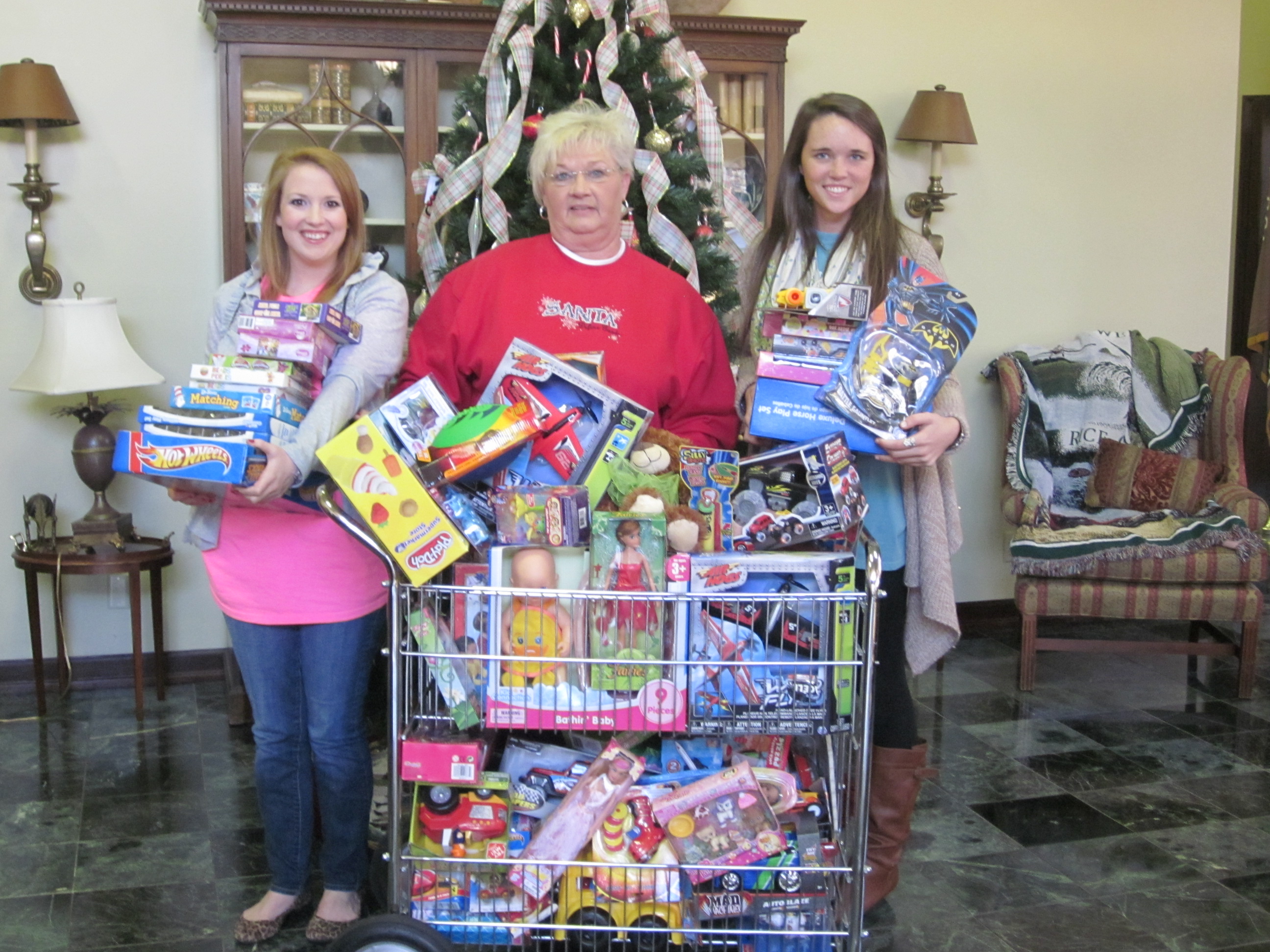 PHOTO:  From left, Amy Scott, Jo Donna Watson, and Shelby McIntire gather the gifts that were donated to the toy drive.