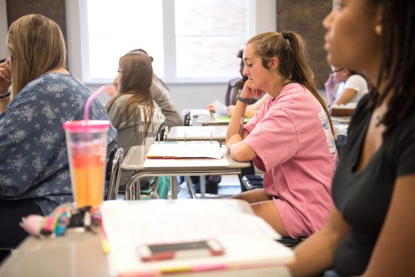 Students in class sitting at desks with notebooks open.