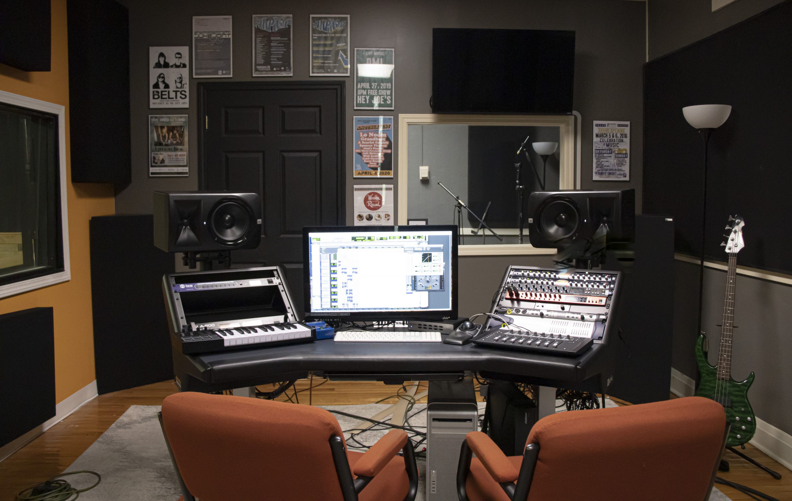 Small recording studio with recording equipment on each site of the computer screen.