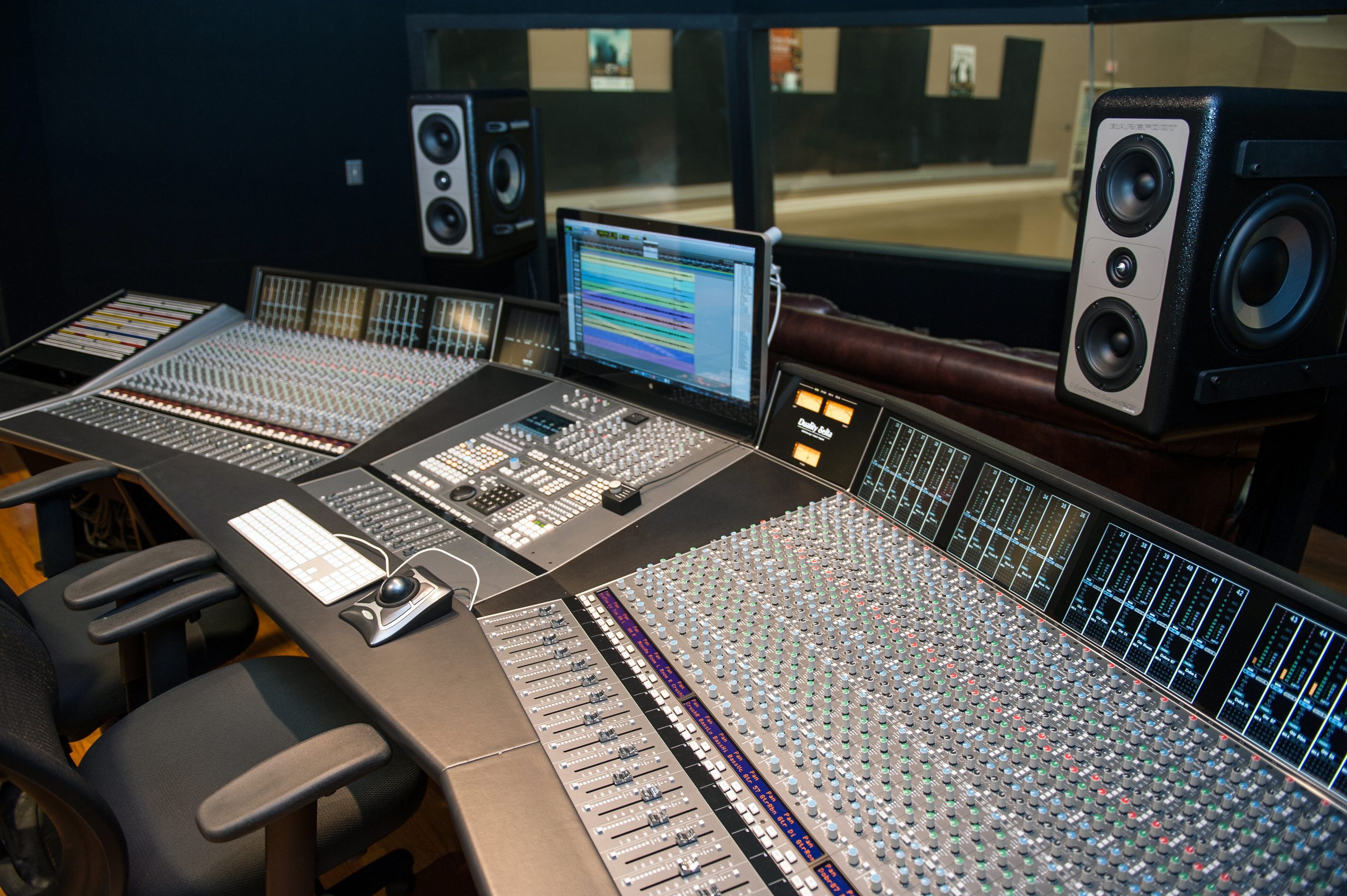 Large studio console powered on in the control room.