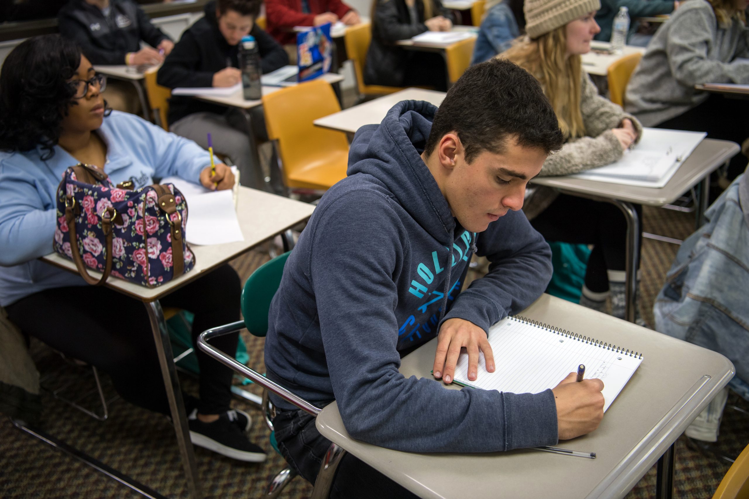 Athletic male student taking notes in class.