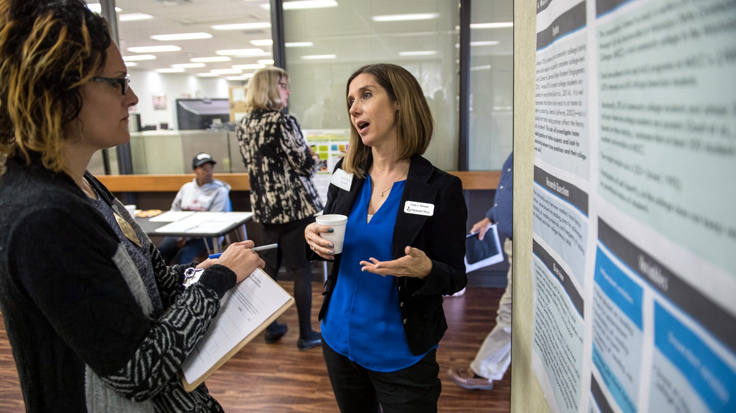 Doctoral student presenting research findings to another working professional at doctoral research student symposium.