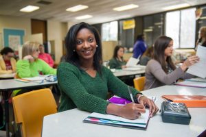 Student in teacher education classroom, completing assignment.