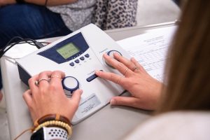 Student using hearing test equipment on a desk in a classroom setting.