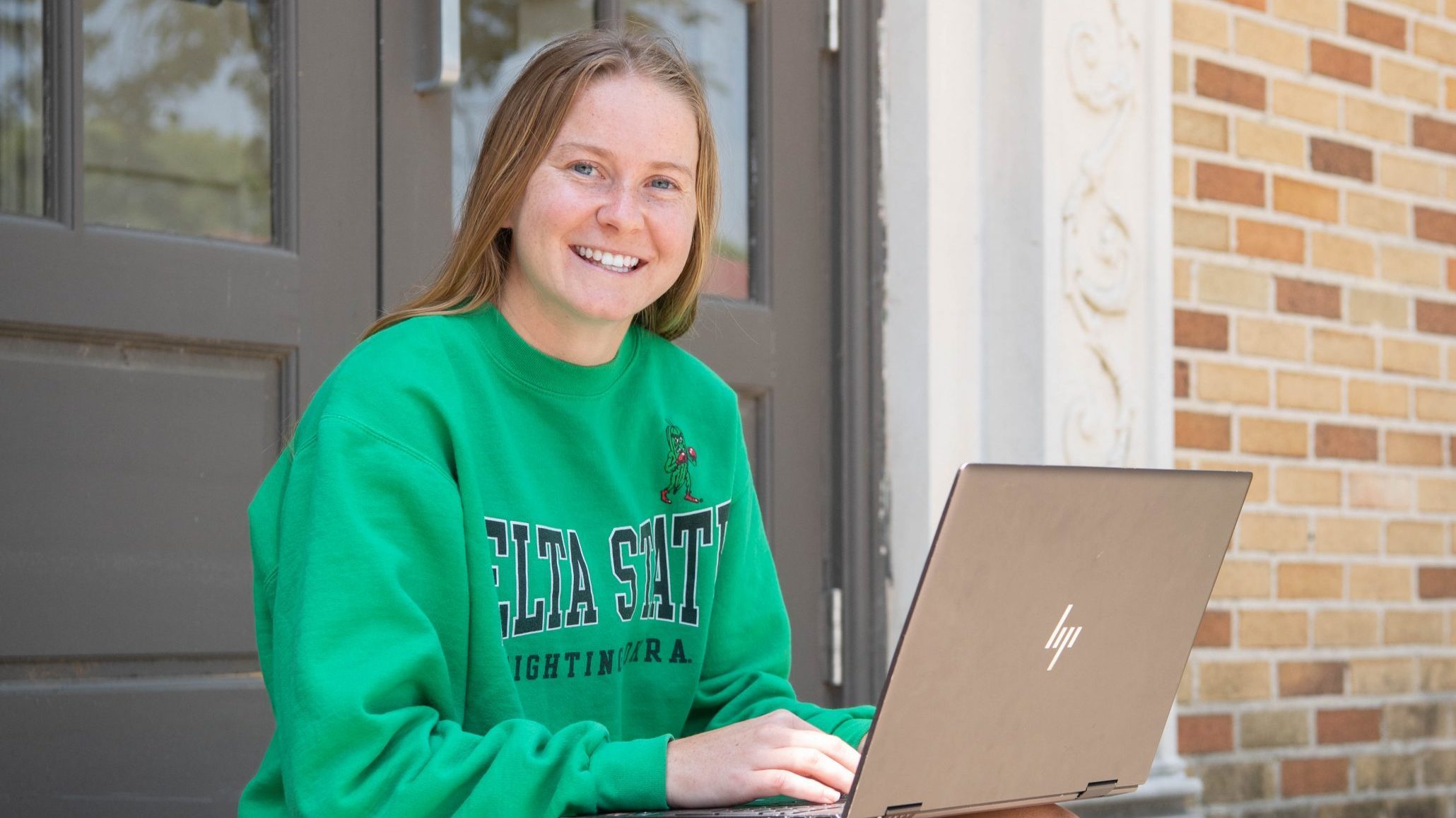 Student on laptop in Delta State hoodie, completing assignments.