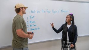 A male and female student listing the four types of managers on a whiteboard.
