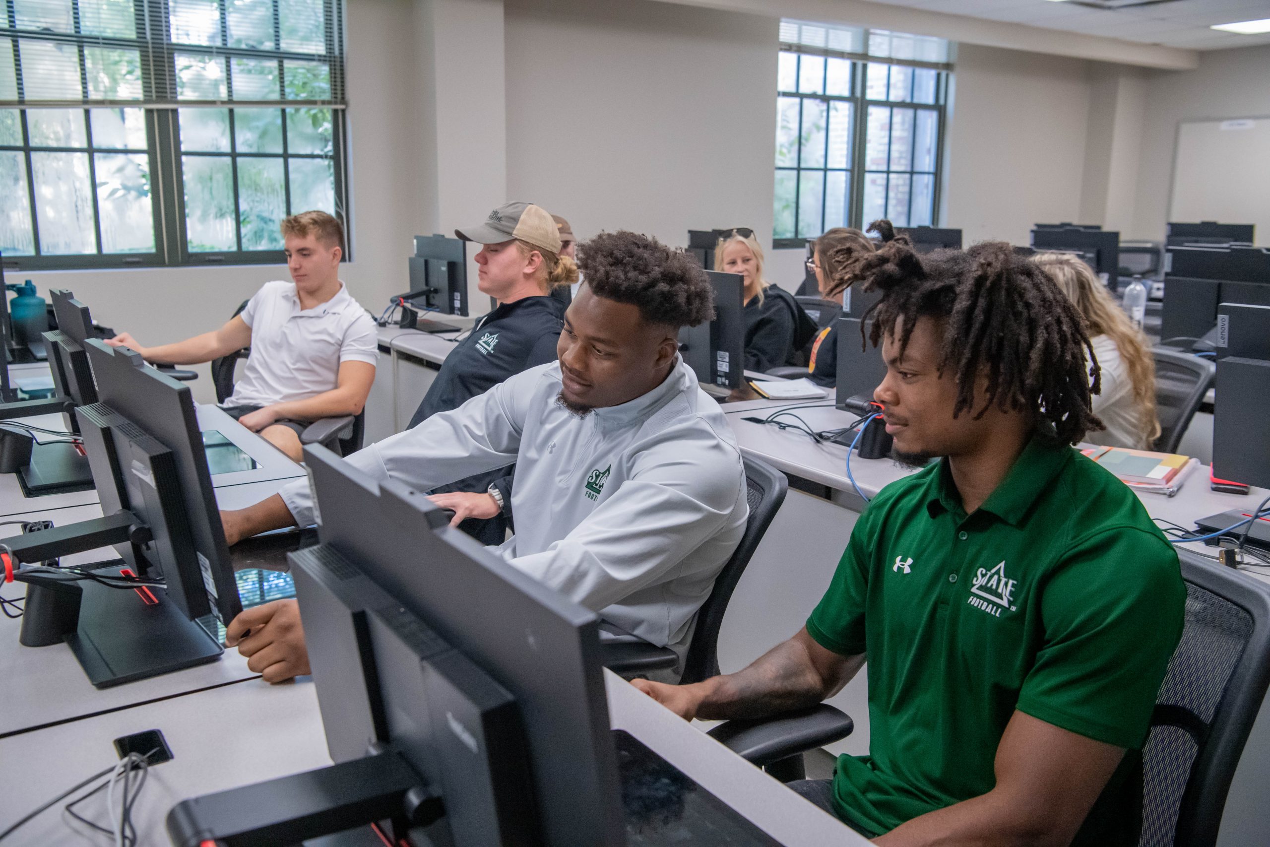 Eight students in a computer lab, working on a assignment together in pairs