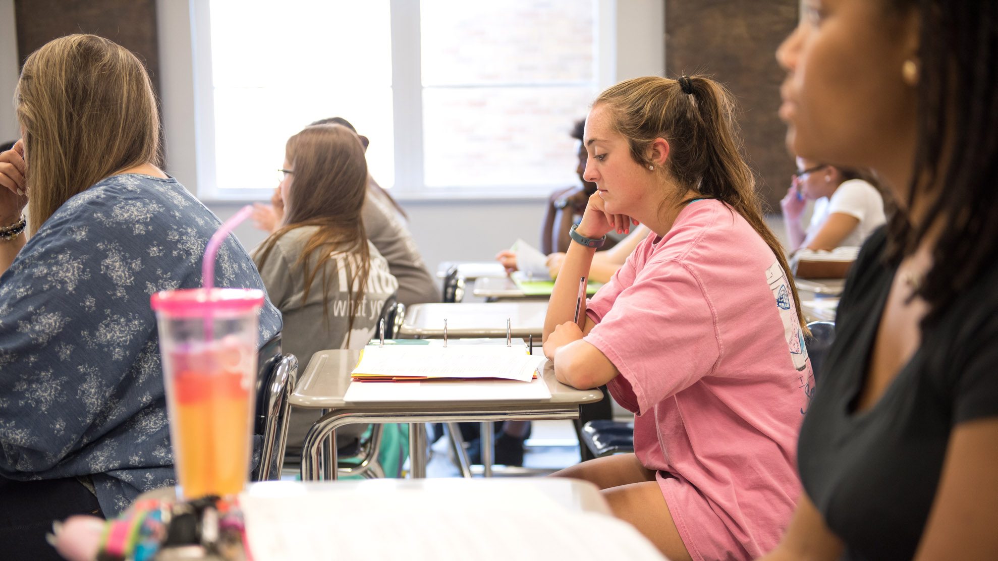 Students in class sitting at desks with notebooks open.