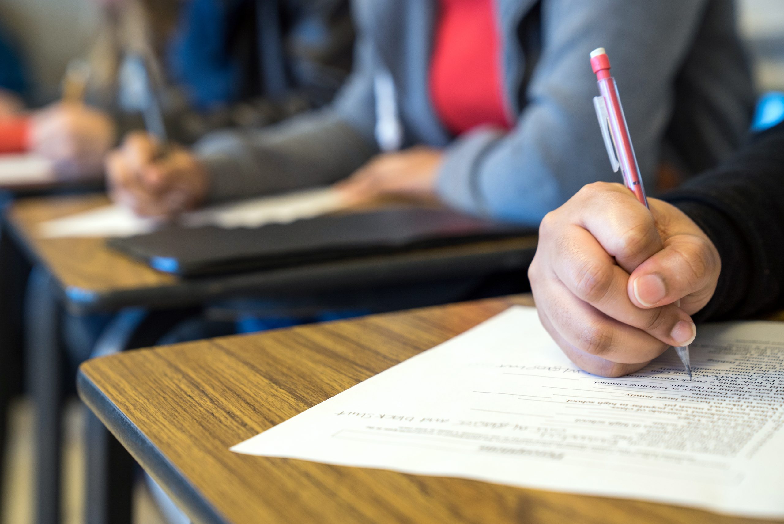 A students hand writing with a mechanical pencil on a handout given out during class.
