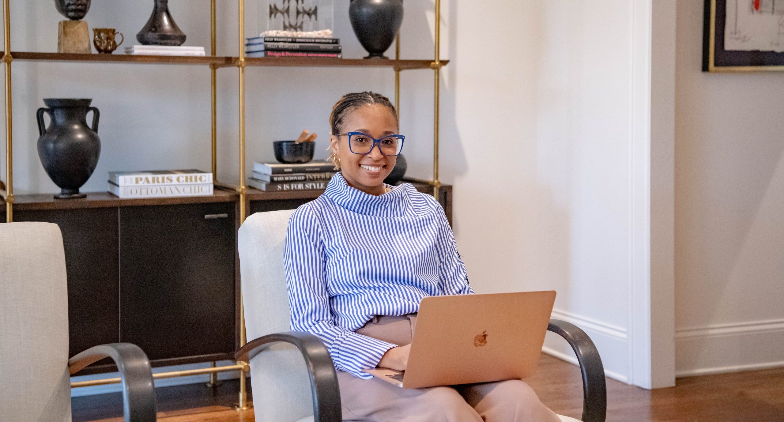 Student sitting in chair in living room with laptop in her lap.