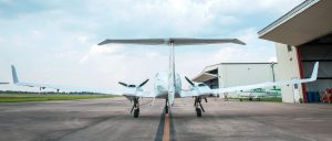 A twin-engine aircraft parker on an airport runway near hangars.