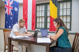 Two students working on assignment together in the College of Business and Aviation, both with a laptops and textbooks.