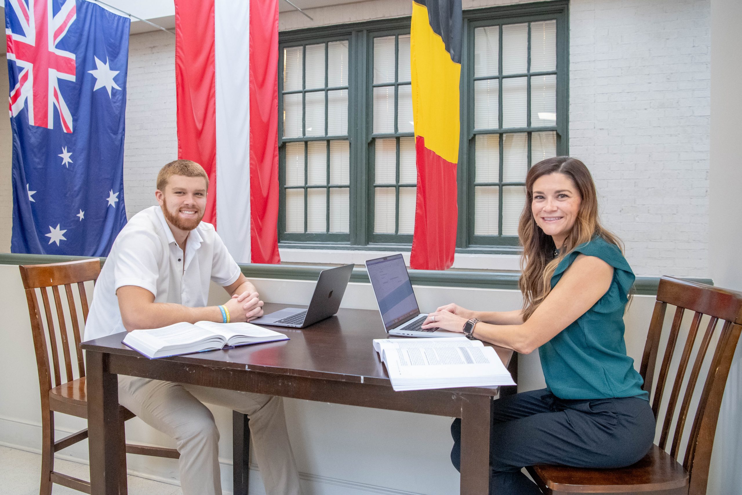 Two students working on assignment together in the College of Business and Aviation, both with a laptops and textbooks.