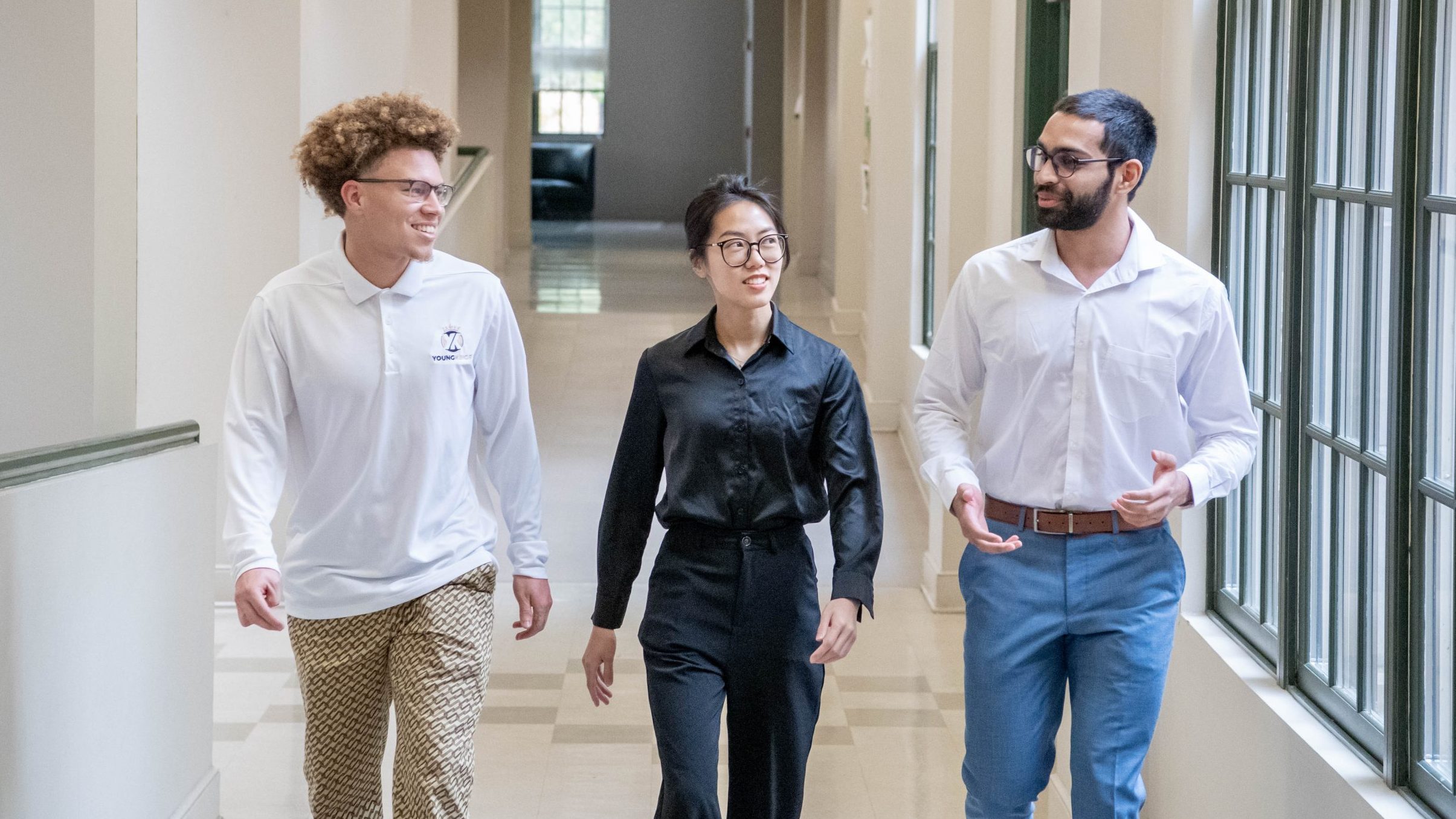 Three students walking and talking in the College of Business and Aviation lobby.