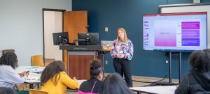 Student presenting PowerPoint information in front of a classroom.