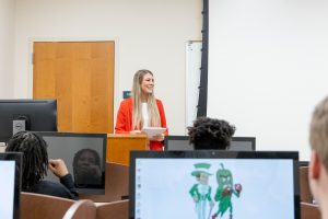 Student presenting information in front of students in a computper lab.
