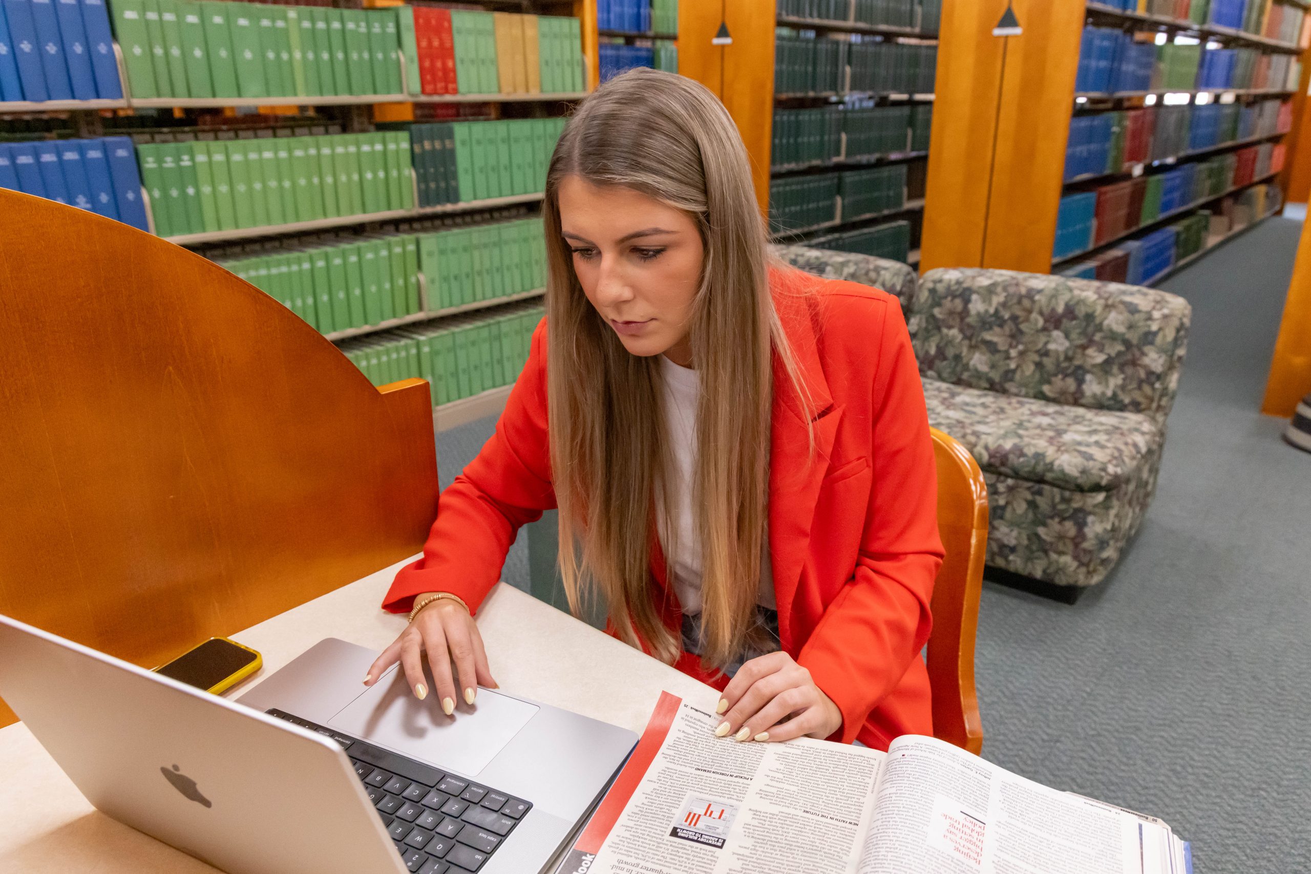 Student sitting at a desk in the library, looking at a laptop.