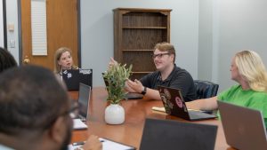 Delta State University staff in a conference room meeting, with one person speaking and others listening.