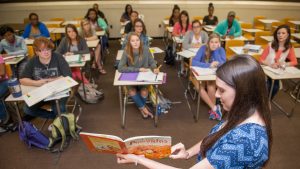 Student presenting children's book to classroom.