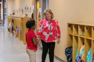 School administrator giving an elementary student a high-five in the hallway.