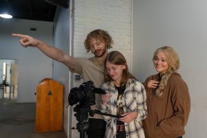 Students collaborating on a film project with professional camera equipment during a media production class.