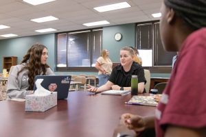 Students sitting around a table engaged in discussion in a classroom.