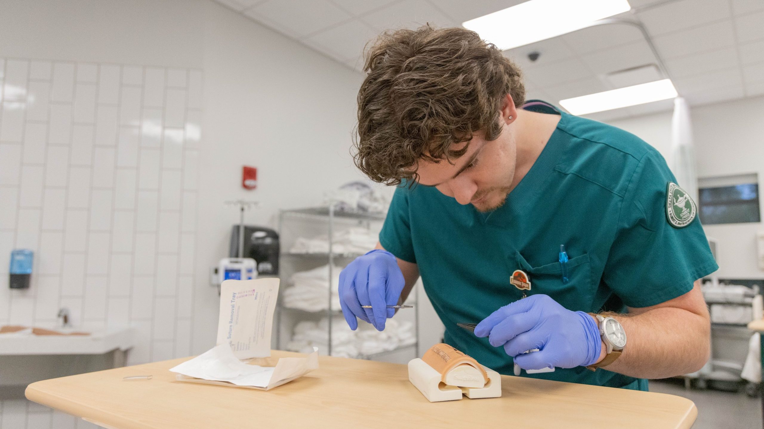 Nursing student practicing suturing techniques in a clinical simulation lab.