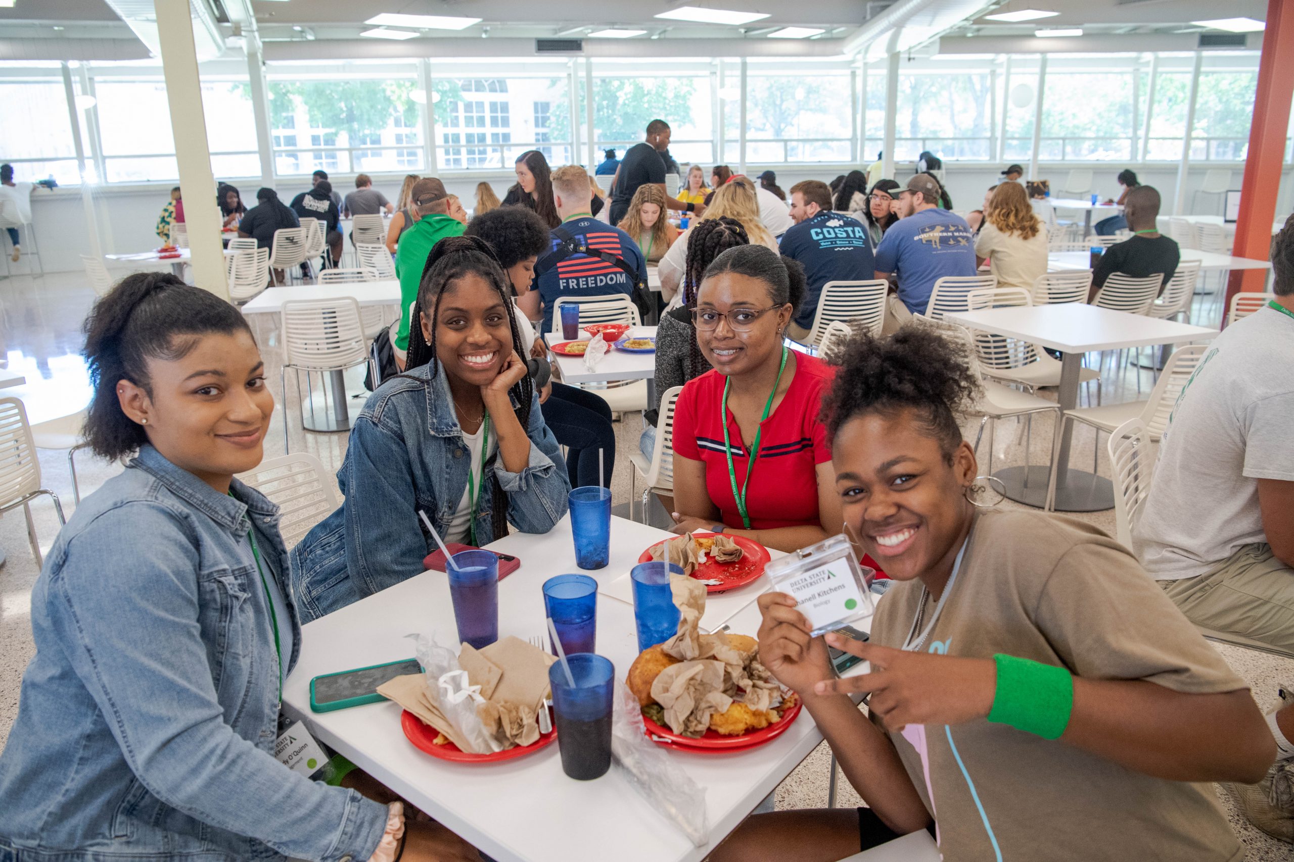 4 young ladies finishing lunch at a table in the cafeteria.