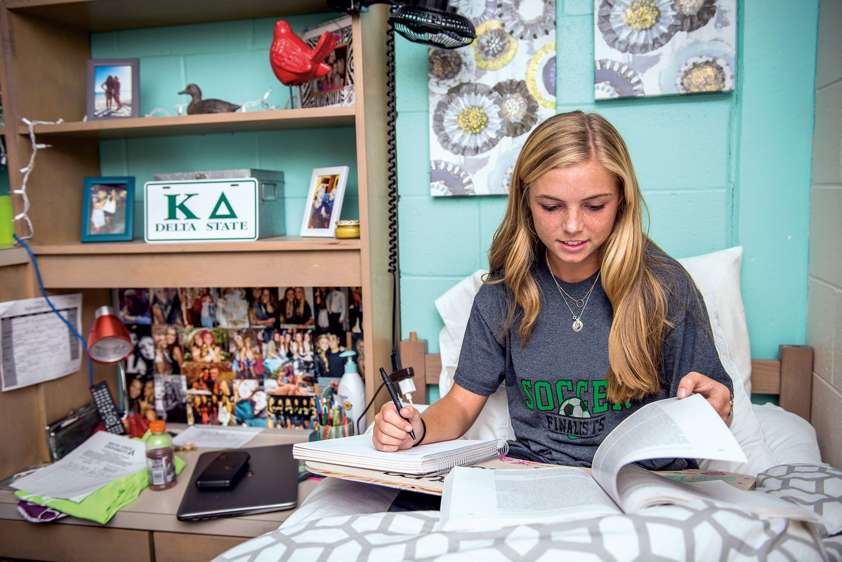 A girl studies in bed in a decorated Delta State freshman residence hall room.