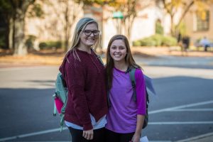 Two student walking to class and smiling.