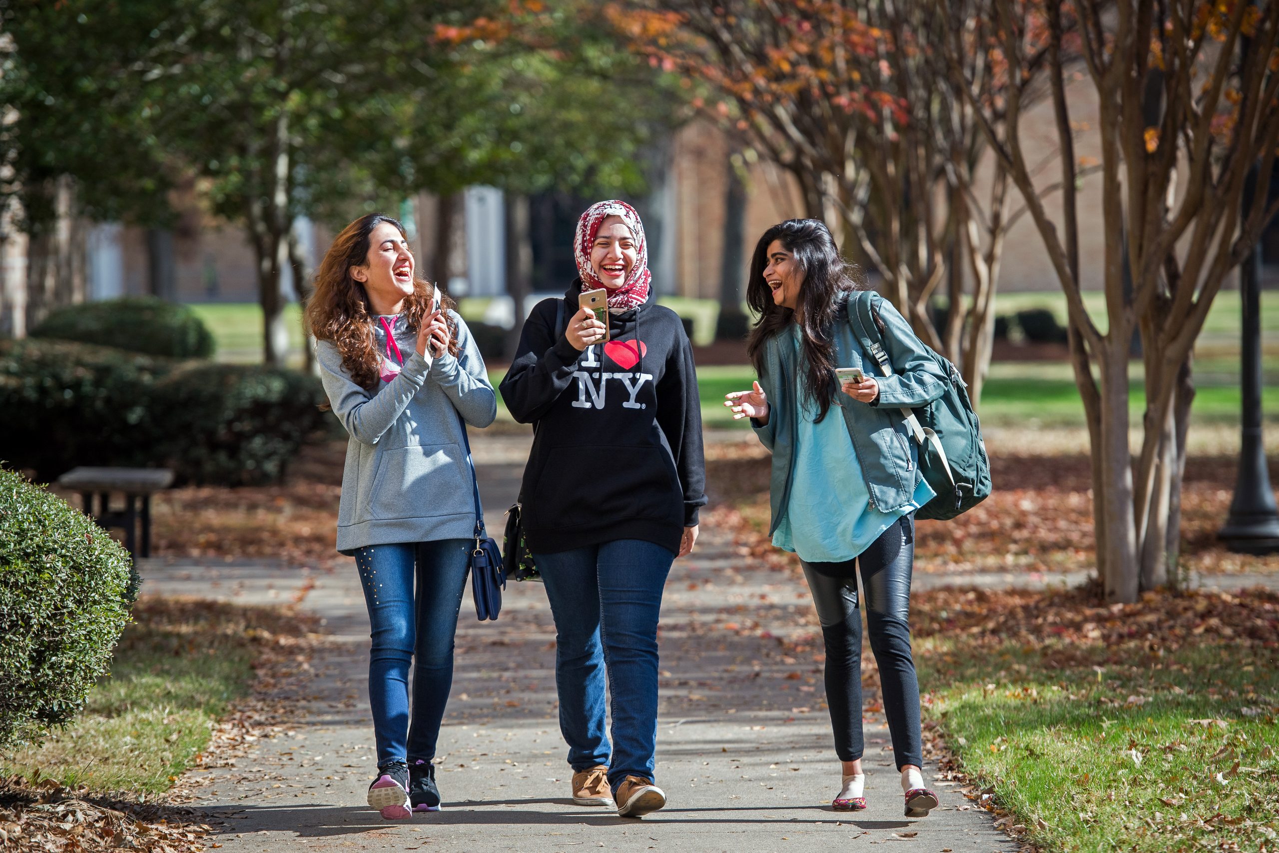 3 International students walking and having fun on campus.