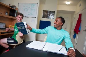2 young men completing homework in residence hall room.