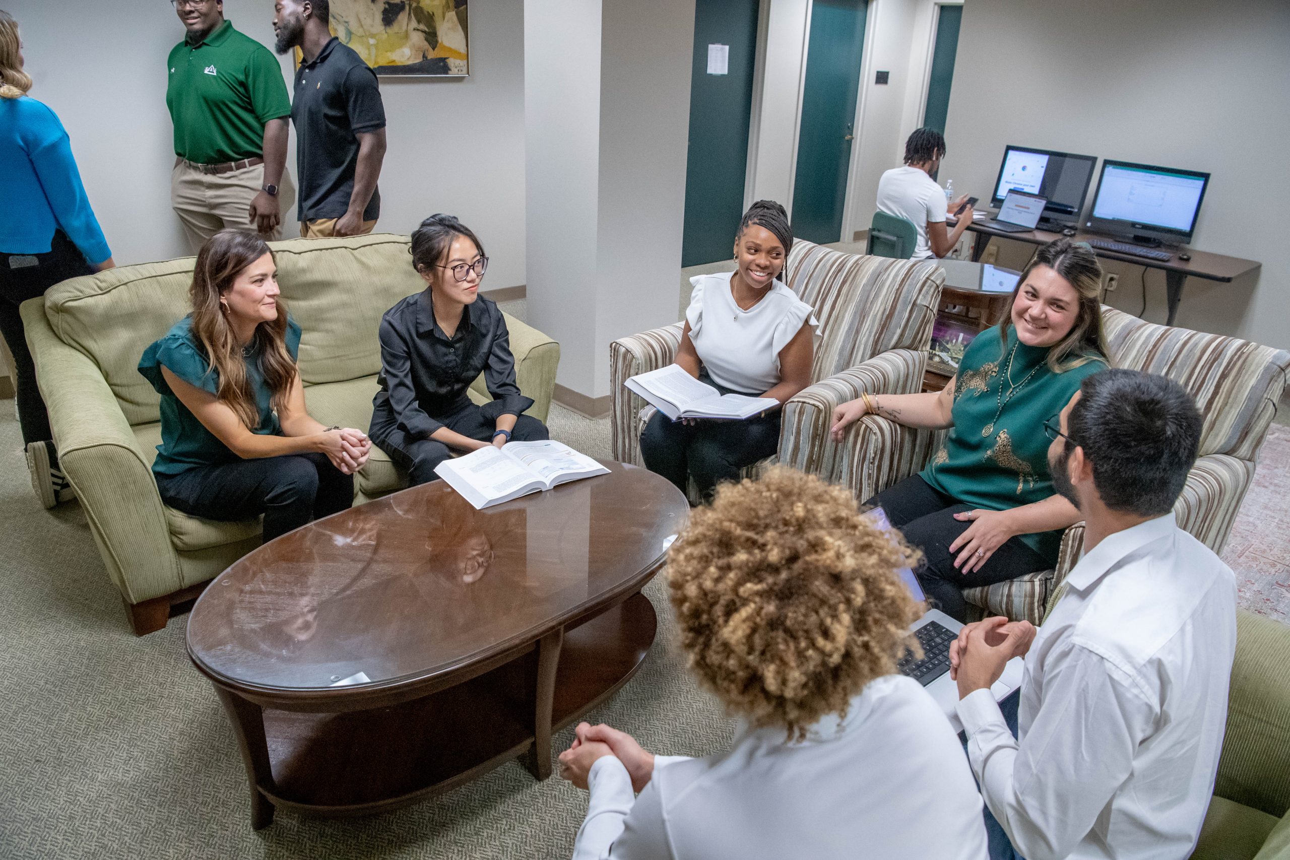 Students sitting together in a lounge area discussing coursework.