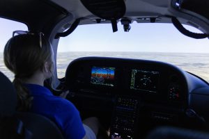 Student pilot practicing in a flight simulator with digital instrument displays.