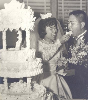 Bride feeds wedding cake to groom, B&W.