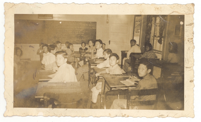 Photo of children at school desks, B&W.