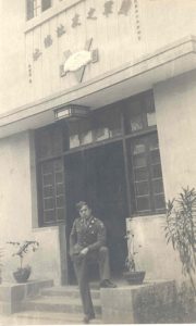 Photo of Mr. Chow in uniform posing on stoop, B&W.
