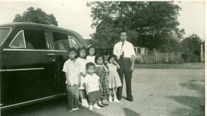 Family posing in front of car, B&W.