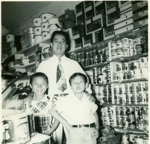 Man poses with 2 children in store. B&W.
