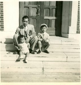 Man with 2 children posing on church stoop, B&W.