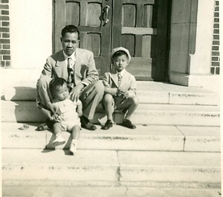 Man with 2 children posing on church stoop, B&W.