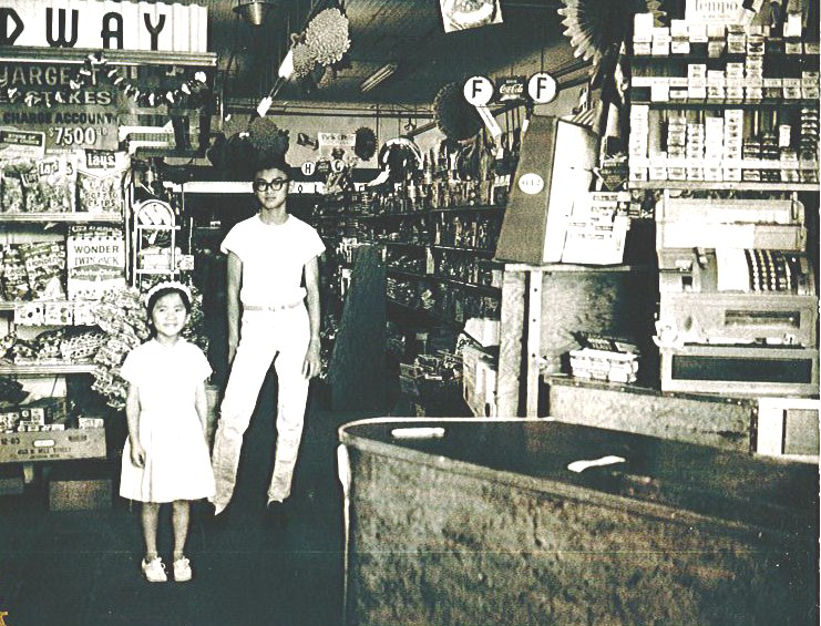 A young girl stands next to a young man in a grocery store.