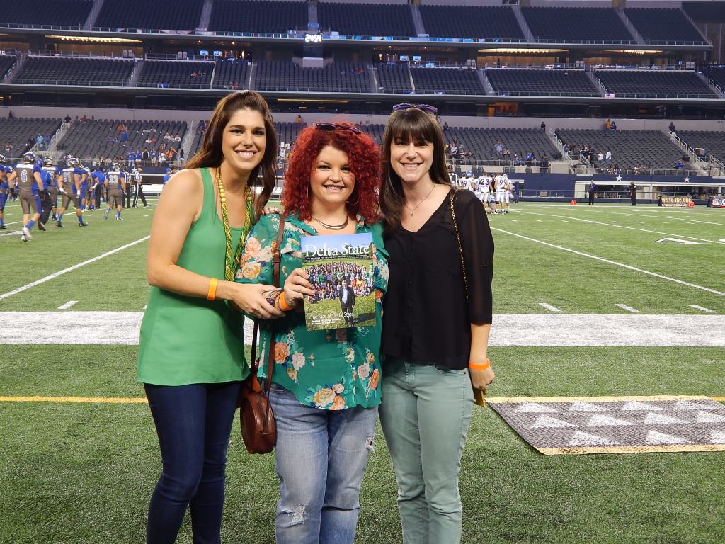 Graduates pose with alumni magazine at ATT stadium