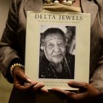 An attendee holds a copy of the Delta Jewels book.