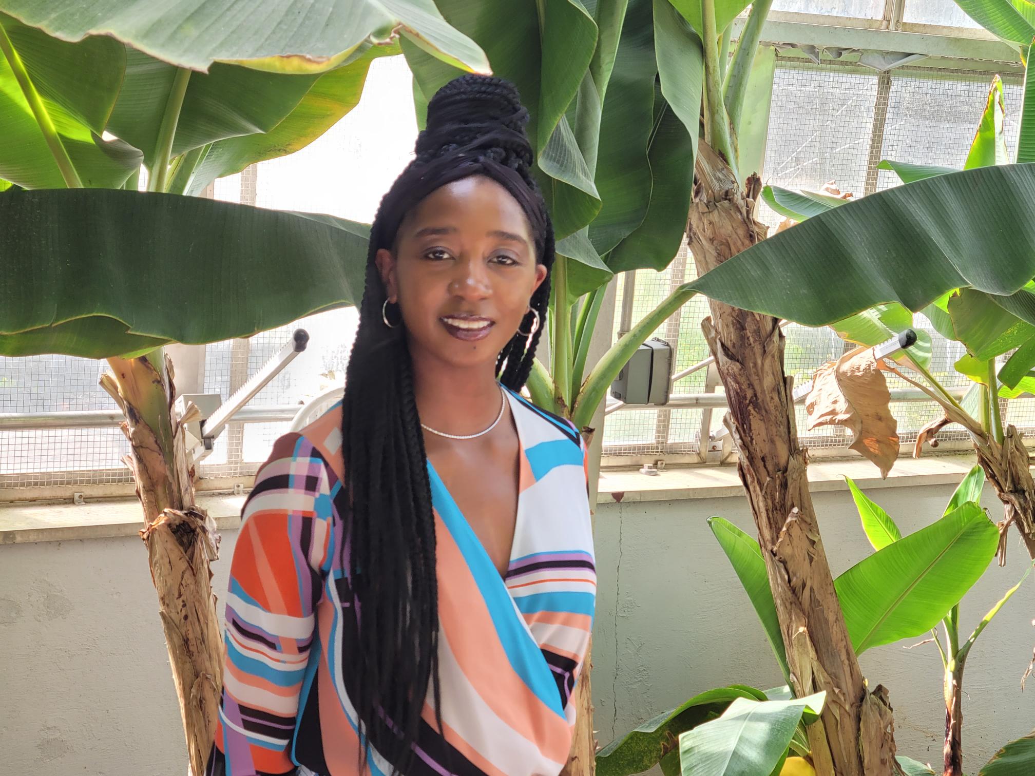a young woman standing in front of banana trees