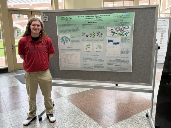 a young man standing next to a poster.