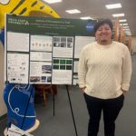 Erick Manriquez stands next to his research poster at the Academic Research Showcase.