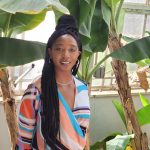 a young woman standing in front of banana trees